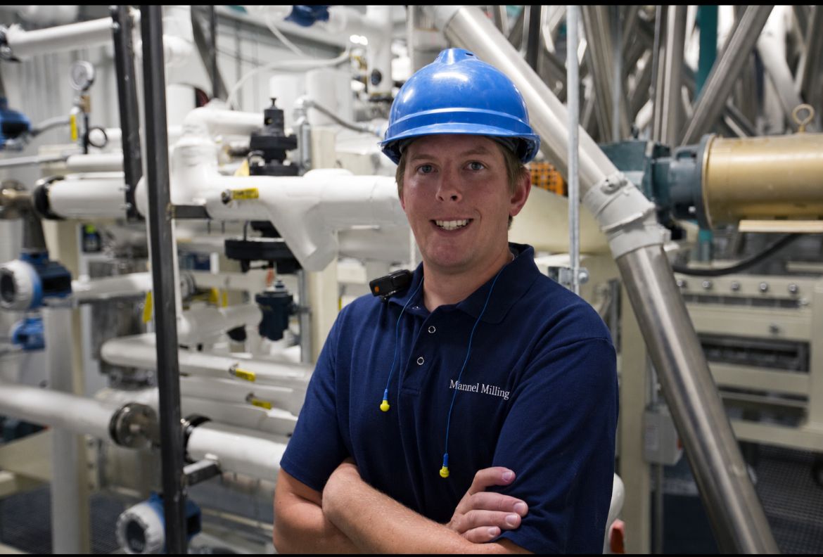 Employee stands against milling equipment